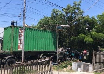 Sebuah truk kontainer terjebak dahan pohon di jalan Prof Dr Aloei Saboe Kota Gorontalo yang membuat arus lalu lintas macet.(F. Rama/gopos)