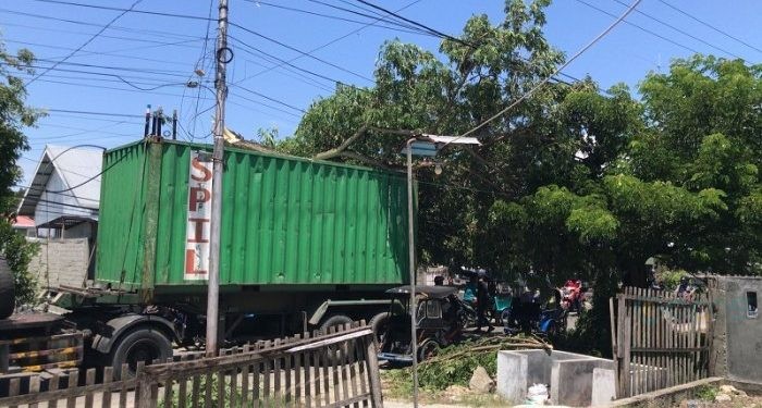 Sebuah truk kontainer terjebak dahan pohon di jalan Prof Dr Aloei Saboe Kota Gorontalo yang membuat arus lalu lintas macet.(F. Rama/gopos)