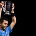 Jonatan Christie mengangkat piala di podium usai memenangi final tunggal putra All England 2024 di Utilita Arena, Birmingham, Inggris, 17 Maret 2024. [JUSTIN TALLIS / AFP]