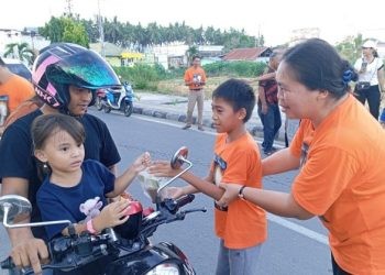 Salah satu anak-anak dari jemaat kristen membagikan takjil kepada pengendara yang melintas di Komplek Blok Plan Perkantoran Marisa.