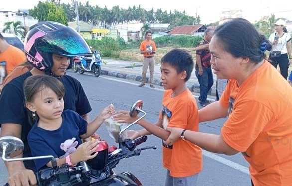 Salah satu anak-anak dari jemaat kristen membagikan takjil kepada pengendara yang melintas di Komplek Blok Plan Perkantoran Marisa.