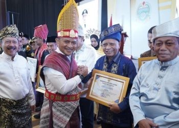 Pj Gubernur Sumut Hasanuddin bersama Bupati Asahan Surya menggunakan pakaian adat pada Musrenbang RKPD 2025.