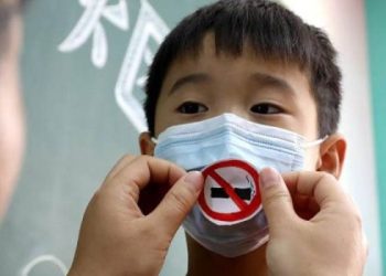 Petugas layanan masyarakat membantu seorang anak memakai masker dengan tanda antimerokok, bagian dari rangkaian Hari Tanpa Tembakau Sedunia 31 Mei, di Shijiazhuang, Provinsi Hebei, China utara (30/5/2020). ANTARA/Xinhua/Wang Xiao/aa.