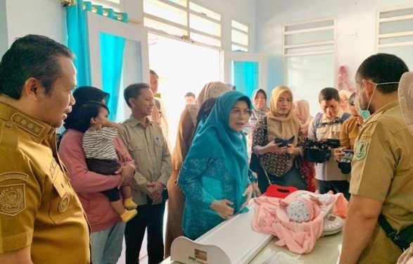 Penjabat Gubernur Gorontalo Ismail Pakaya dan Ketua Tim Penggerak PKK Provinsi Fima Agustina saat membawa cucunya ke Posyandu Cengkih 1 Kelurahan Tenda Kecamatan Hulonthalangi Kota Gorontalo.
