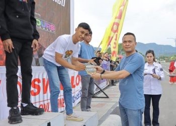 Kapolres Bone Bolango, AKBP Muhammad Alli saat menyerahkan piala dan bonus kepada pemenang drag bike, Minggu (12/5/2024). (Foto Noldi/Humas Polres Bone Bolango)