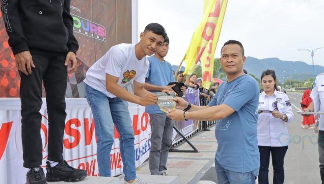 Kapolres Bone Bolango, AKBP Muhammad Alli saat menyerahkan piala dan bonus kepada pemenang drag bike, Minggu (12/5/2024). (Foto Noldi/Humas Polres Bone Bolango)