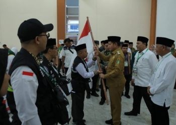 Pj Gubernur Sumut Hassanudin saat melepas jemaah calon haji kloter 1 Asahan secara simbolis dengan menyerahkan bendera kepada petugas haji di Asrama Haji Medan, Senin (13/5/2024)