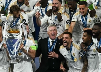 Pelatih Real Madrid Carlo Ancelotti (tengah) dan para pemainnya merayakan dengan trofi setelah pertandingan sepak bola final Liga Champions 2023/2024 antara Real Madrid melawan Borussia Dortmund di Stadion Wembley, London, Inggris, Sabtu (1/6/2024). [Ben Stansall / AFP]