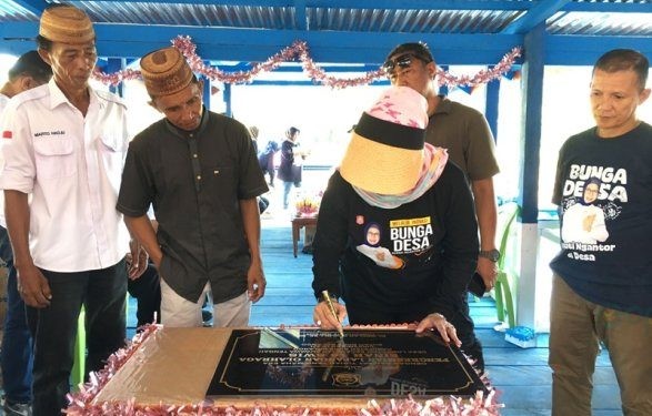 Bupati Merlan S. Uloli didampingi tokoh masyarakat Suwawa Tengah, Arifin Maliwu saat menandatangani prasasti peresmian lapangan bola voli. (Foto Indra/Gopos)