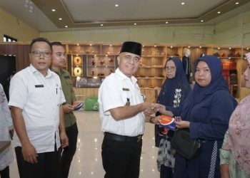 Asisten Perekonomian dan Pembangunan menyerahkan buku tabungan dana pinjaman bergulir secara simbolis kepada pelaku usaha mikro.