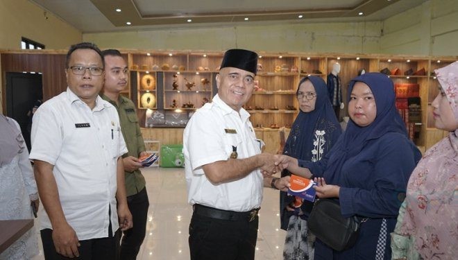 Asisten Perekonomian dan Pembangunan menyerahkan buku tabungan dana pinjaman bergulir secara simbolis kepada pelaku usaha mikro.