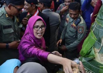 Bupati Blitar Rini Syarifah saat turut berebut olahan tradisional yang ada di gunungan tujuh saat Larung Sesaji di Pantai Serang, Kecamatan Panggungrejo, Kabupaten Blitar, Selasa, 9 Juli 2024. (Foto: Pemkab Blitar)