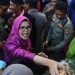 Bupati Blitar Rini Syarifah saat turut berebut olahan tradisional yang ada di gunungan tujuh saat Larung Sesaji di Pantai Serang, Kecamatan Panggungrejo, Kabupaten Blitar, Selasa, 9 Juli 2024. (Foto: Pemkab Blitar)