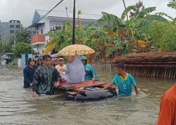 Beberapa orang warga mengevakuasi seorang ibu rumah tangga dan balita menggunakan rakit seadanya pada banjir di wilayah Kota Gorontalo, Kamis (11/7/2024). (Foto Sari/gopos)