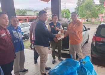 Pj Sekda Bone Bolango, Aznan Nadjamudin saat menyerahkan bantuan paket sembako kepada warga Kecamatan Bone yang terdampak banjir