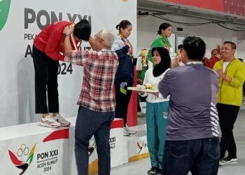 Pj Gubernur Gorontalo Rudy Salahuddin mengalungkan medali emas kepada atlet taekwondo Silvana Lamanda di GOR Martial Arts Arena, Medan, Kamis (12/9/2024).
