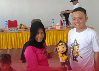 Anggota KPU Gorut Noval Katili menyerahkan boneka maskot Pilkada kepada warga Anggrek setelah kegiatan sosialisasi, Senin (28/10/2024).
