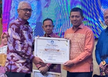Penjabat Gubernur Gorontalo, Rudy Salahuddin saat menyerahkan Piagam Penghargaan kebijakan Merdeka Belajar kepada Kepala Dinas Pendidikan dan Kebudayaan Kabupaten Bone Bolango, Adrien Andjar di Hotel Aston Kota Gorontalo, Minggu (20/10/2024). (Foto Istimewa)