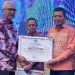 Penjabat Gubernur Gorontalo, Rudy Salahuddin saat menyerahkan Piagam Penghargaan kebijakan Merdeka Belajar kepada Kepala Dinas Pendidikan dan Kebudayaan Kabupaten Bone Bolango, Adrien Andjar di Hotel Aston Kota Gorontalo, Minggu (20/10/2024). (Foto Istimewa)