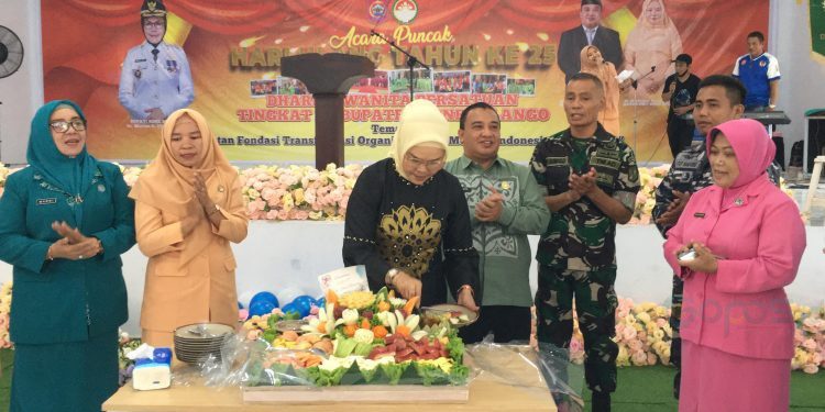 Bupati Merlan S. Uloli saat melakukan pemotongan tumpeng buah pada perayaan Hari Ulang Tahun (HUT) ke-25 Dharma Wanita Persatuan (DWP) yang dilaksanakan di Bandayo Li Mbui, Kecamatan Kabila, Jumat (13/12/2024). (Foto Indra/Gopos)