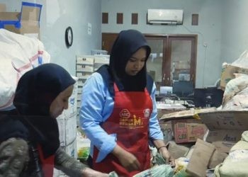 Dua staf Foodbank of Indonesia sedang membongkar produk hasil donasi untuk segera diolah di dapur bersama. ANTARA/Mardiansyah Al Afghani