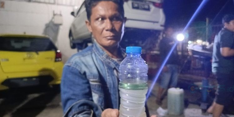 Pemilik mobil yang menunjukkan Pertalite yang bercampur air usai mengisi BBM di SPBU Marisa, Kamis malam (5/12/2024).(Foto Irfan/Istimewa)