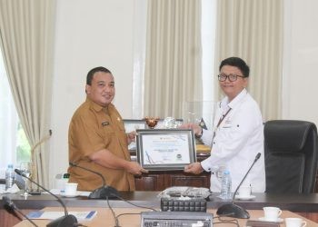 Pjs Kepala Ombudsman RI Perwakilan Provnsi Gorontalo, Lucky Puspito Rantung saat menyerahkan langsung piagam penghargaan penganugerahan predikat penilaian kepatuhan penyelenggaraan pelayanan publik tahun 2024 kepada Pemerintah Kabupaten Bone Bolango yang diterima langsung oleh Pj Sekretaris Daerah Bone Bolango Reflin Buata di Ruang Rapat Bupati Bone Bolango, Senin (16/12/2024). (Foto Yudi/Prokopim)