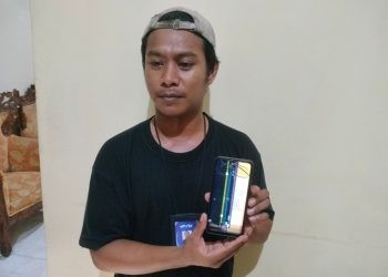 Wartawan RTV Gorontalo Ridha Yansa saat memperlihatkan ponselnya rusak usai dipukul oknum perwira Polda Gorontalo ketika meliput unjuk rasa, Senin (23/12/2024).