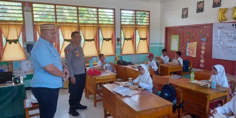 Kapolsek Suwawa Iptu Djon K. Nusi didampingi Camat Suwawa Selatan Ricky Roman Wartabone saat membagikan dan memantau program Makanan Bergizi Gratis di SDN 1 Suwawa Selatan. (Foto Istimewa)