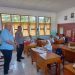 Kapolsek Suwawa Iptu Djon K. Nusi didampingi Camat Suwawa Selatan Ricky Roman Wartabone saat membagikan dan memantau program Makanan Bergizi Gratis di SDN 1 Suwawa Selatan. (Foto Istimewa)