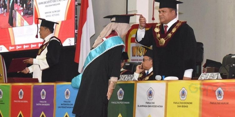 Rektor UNG Eduart Wolok memindahkan tali toga ke salah satu wisudawati di auditorium UNG (Foto/UNG)