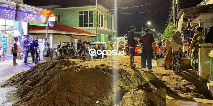 Warga Kelurahan Tenda membawa material pasir bekas longsor ke badan jalan Yos Sudarso sebagai bentuk protes kepada pemerintah yang belum memberi solusi terkait masalah longsor tersebut, Kamis (6/3/2025).(Foto Arif gopos)