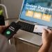 A person is using a laptop to pay for something online. They are holding a credit card and a phone