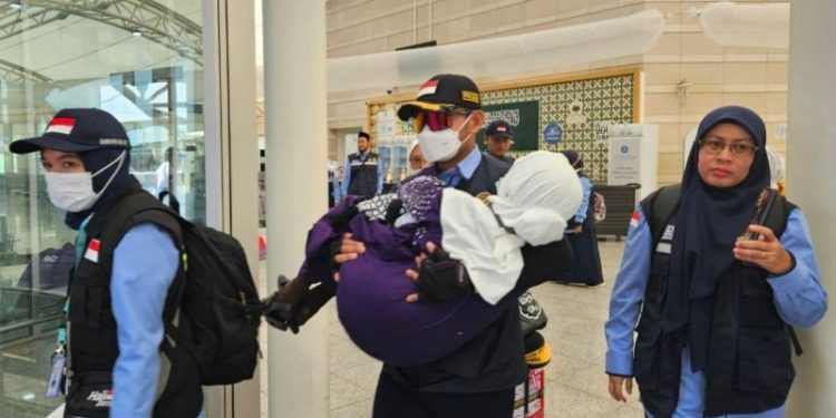 Petugas haji menggendong calon haji Indonesia setibanya di Bandara Amir Muhammad bin Abdul Aziz Madinah. (Foto ANTARA/HO-MCH 2025)