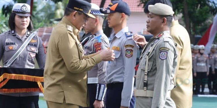 Gubernur Gorontalo Gusnar Ismail saat menyematkan pin dan pita kepada petugas gabungan dalam Apel Gelar Pasukan Operasi Patuh Otanaha 2025, Senin (14/7/2025).(F. Putra Gopos)