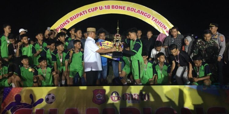 Bupati Ismet Mile saat menyerahkan trofi dan bonus kepada para pemain New Castle FC yang berhasil keluar sebagai juara pada Bupati Bone Bolango Cup U-18 di Lapangan Duano, Suwawa Tengah, Sabtu (11/10/2025). (Foto Indra/Gopos)