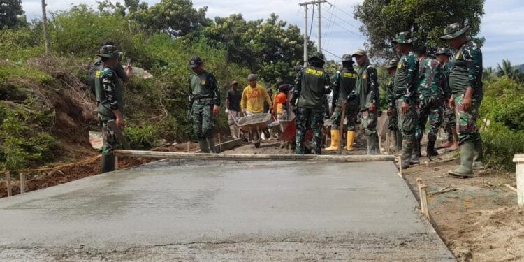 Gotong royong tanpa batas. Warga dan prajurit TMMD ke-126 bahu-membahu menuntaskan rabat beton yang menjadi urat nadi ekonomi desa.(foto.isno gopos)
