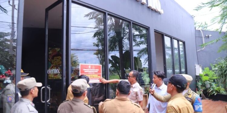 Tim Bapenda Jember menempelkan stiker penunggak pajak di kedai makan Eterno, 22 Desember 2025.