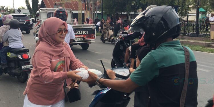 Ketua DWP Bone Bolango, dr.Nurliana Ibrahim saat membagikan takjil kepada masyarakat, Sabtu (!4/3/2026). (Foto Indra/Gopos)