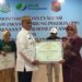 Bupati Ismet Mile saat menyerahkan piagam penghargaan kepada Kecamatan Tilongkabila atas capaian kepesertaan tertinggi di Bone Bolango, Kamis (4/6/2026). (Foto Indra/Gopos)