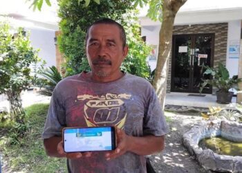 Mohammad As'ari menunjukkan aplikasi mobile JKN. (Foto: Dok/Humas BPJS Kesehatan Cabang Jember)