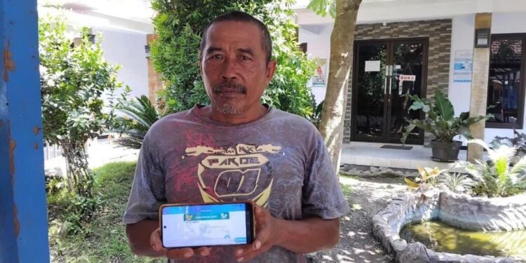 Mohammad As'ari menunjukkan aplikasi mobile JKN. (Foto: Dok/Humas BPJS Kesehatan Cabang Jember)