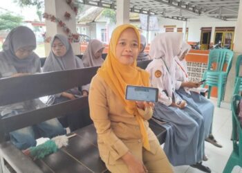Linda Khoirun Nisa menunjukkan layanan Mobile JKN. (Foto: Dok/Humas BPJS Kesehatan Cabang Jember)