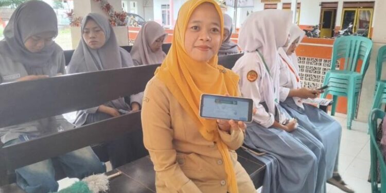 Linda Khoirun Nisa menunjukkan layanan Mobile JKN. (Foto: Dok/Humas BPJS Kesehatan Cabang Jember)