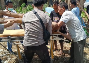 Aparat kepolisian bersama warga setempat saat mengevakuasi korban.(F. Istimewa)