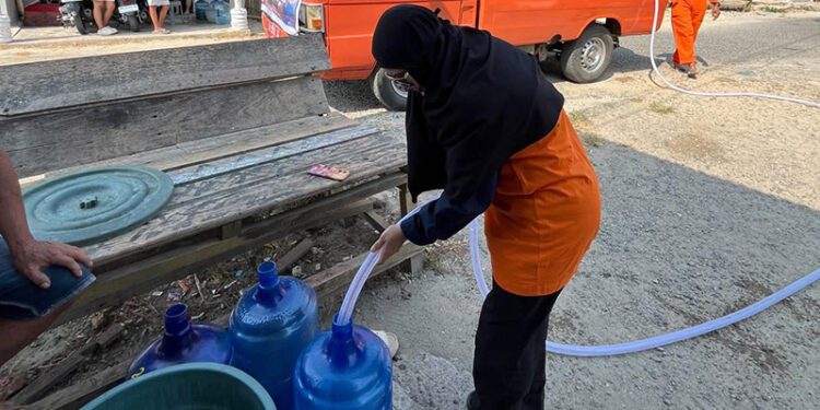 Lusyana Zakaria atau biasa disapa Ka Uchee, petugas BPBD Provinsi Gorontalo yang turut turun langsung membantu menyalurkan air bersih untuk masyarakat Desa Tualango, Kecamatan Tilango, Kabupaten Gorontalo, Senin (21/9/2026).