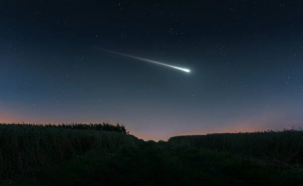 Fireball in the evening sky over the fields. Bright shooting star. Meteor illuminates the starry sky. (Ilustrasi)